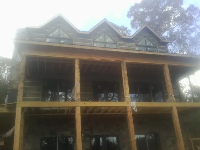 Dormers and porch framing on a large log home under construction — Roof Coating work by our crew in Neenah