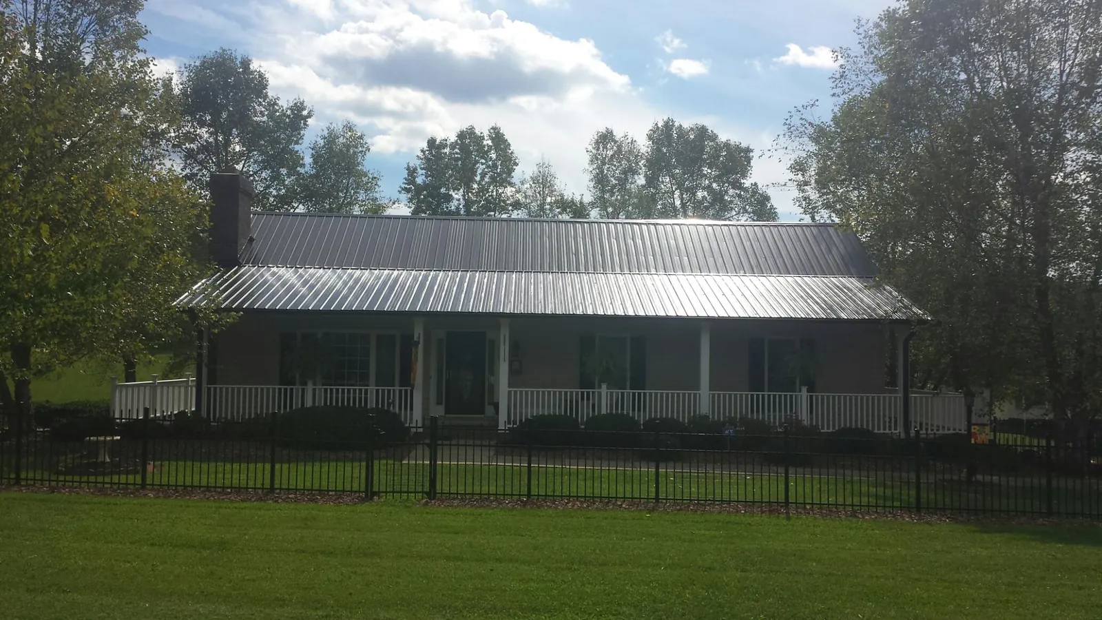 Gray metal roof on a brick ranch with a full width front porch — Gutter Guard Installation work by our crew in Neenah