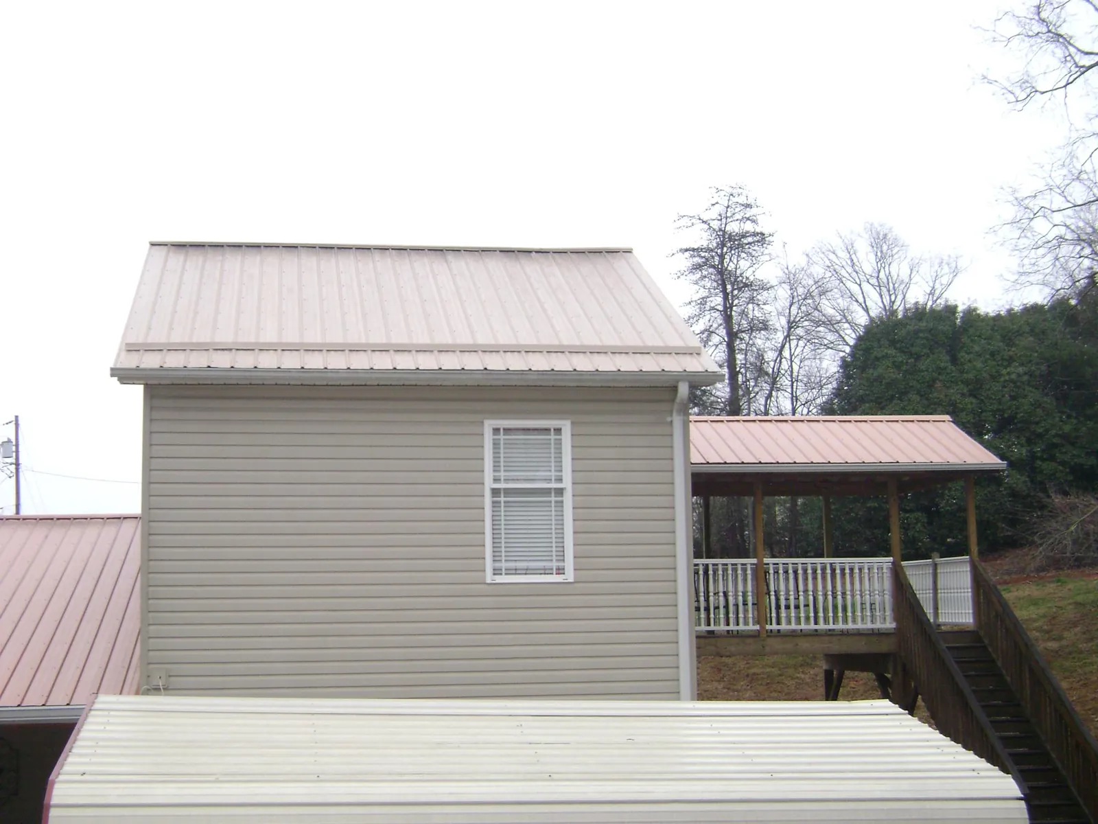 Tan metal roofs on a two story addition and attached porch, from a Roof Replacement job in Neenah